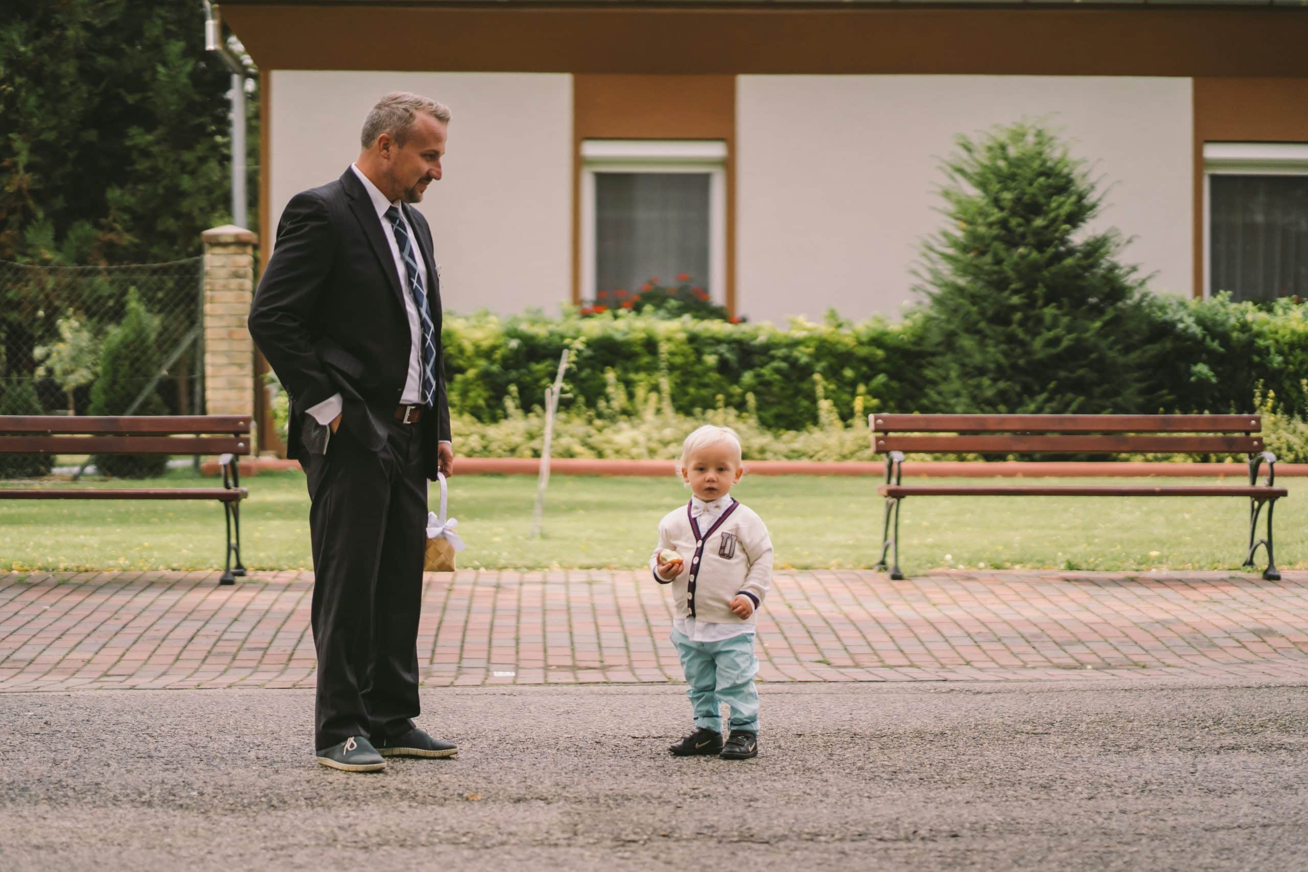 A formally dressed man looking down at a young child
