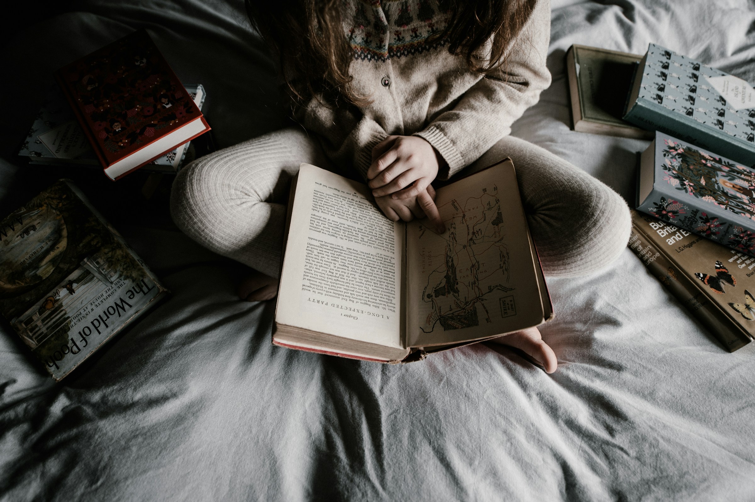 A child reading a pile of books